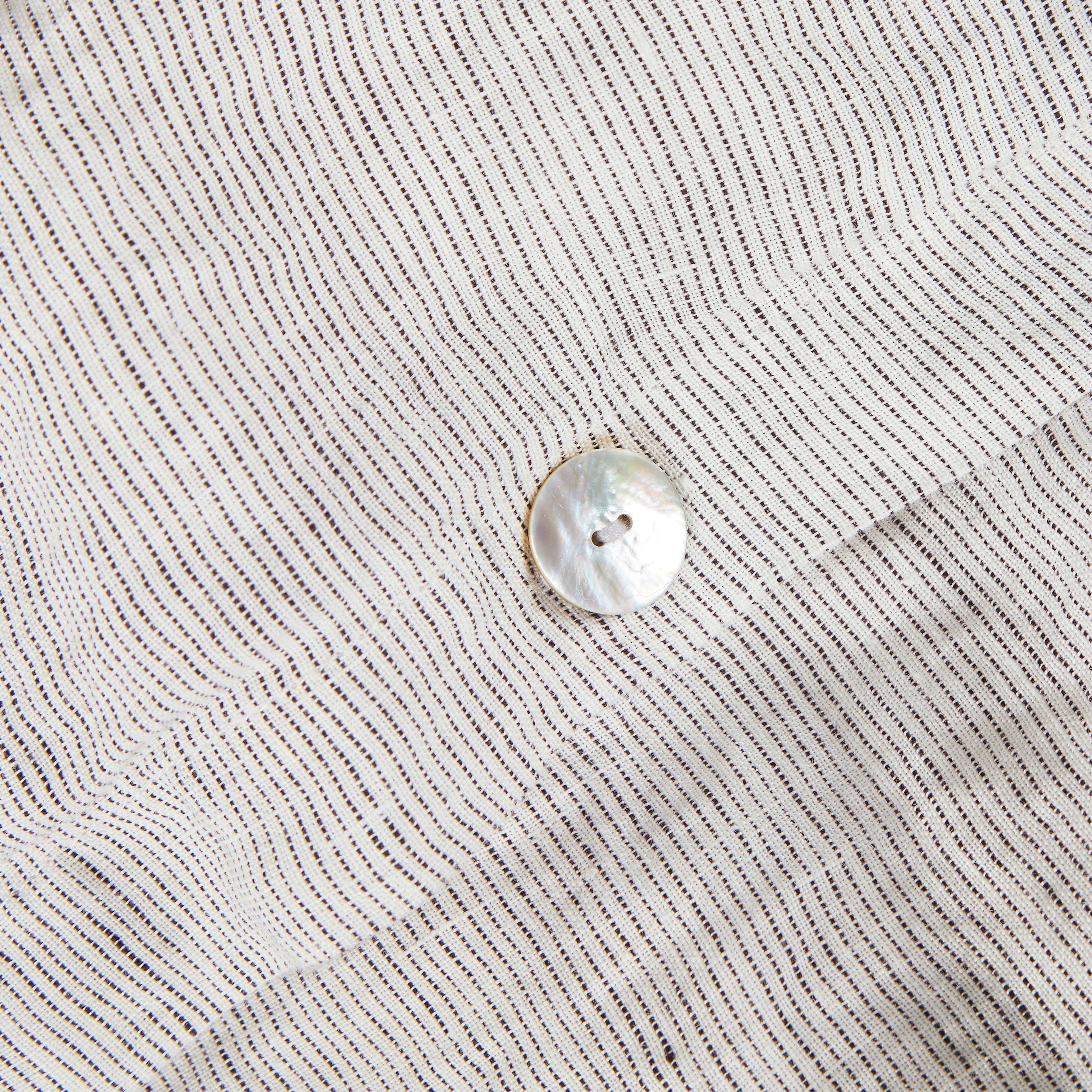 Stoffmuster Leinen grau-weiss gestreift mit Perlmuttknopfdetail. 