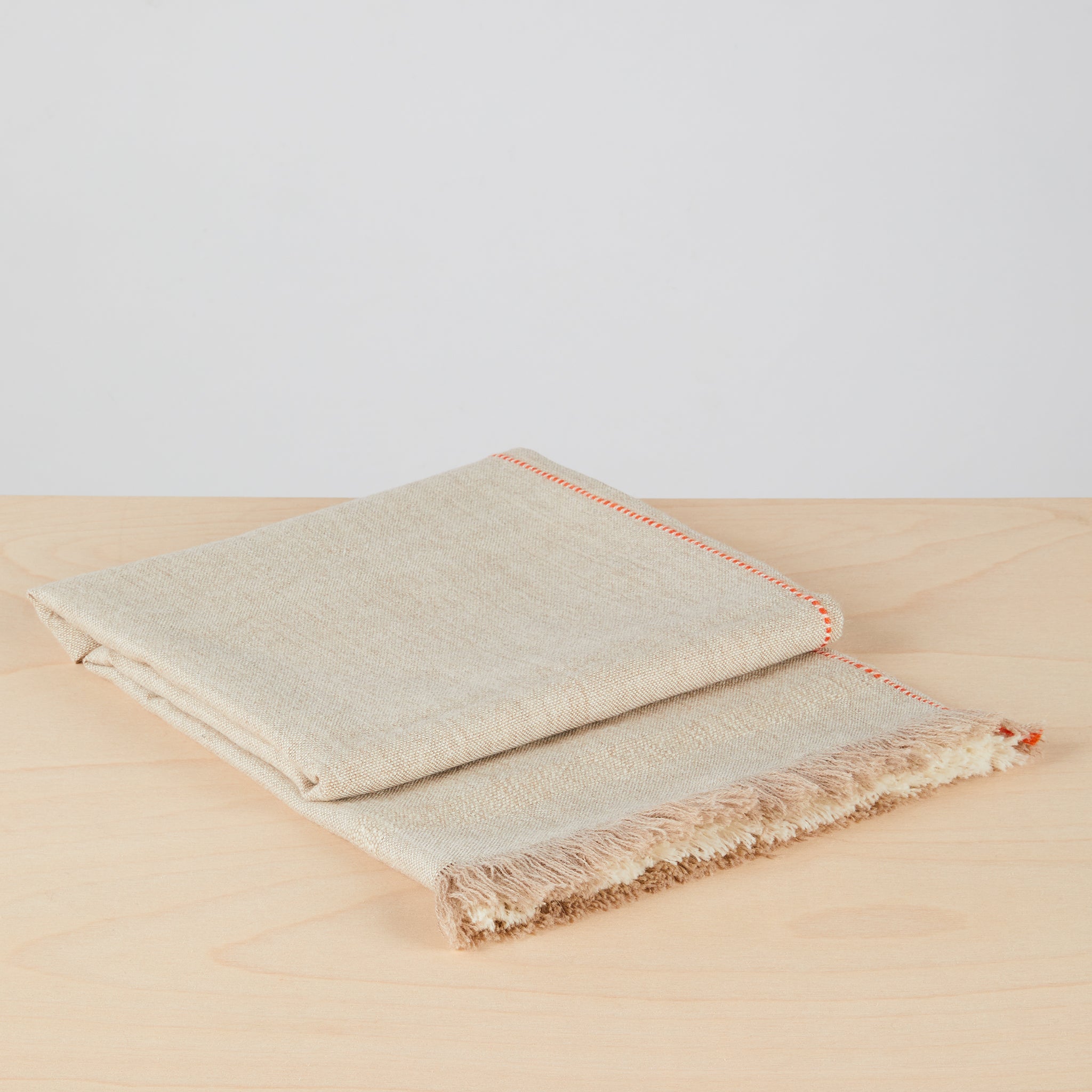 Detailansciht gefaltet:  Stilvolle, handgewebte Decke "Asiri" aus weichem Baby-Alpaka in Naturfarben. Mit Fransen, Hochrelief-Streifen und einem schmalen Kontraststreifen als Eyecatcher.