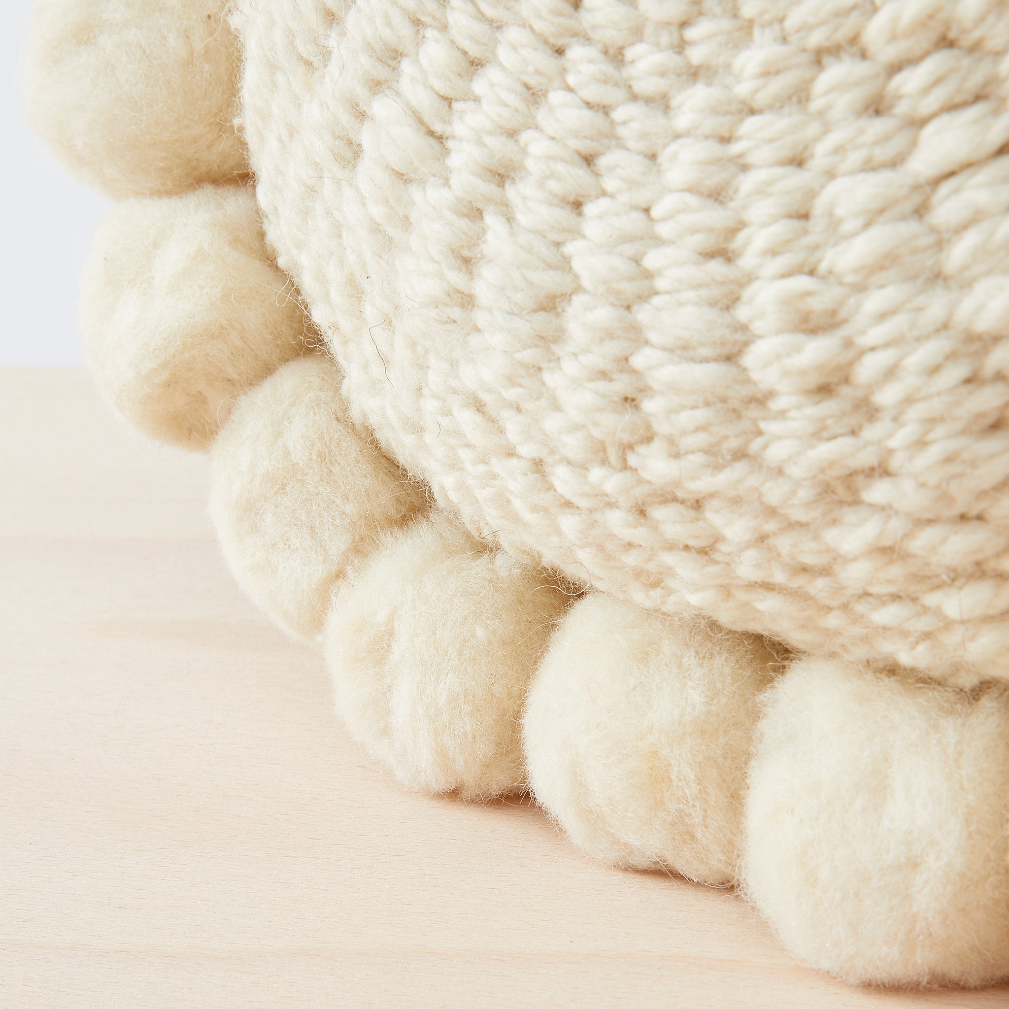 Detailaufnahme Po Pom Kissen aus 100% Schurwolle mit Pom Poms.