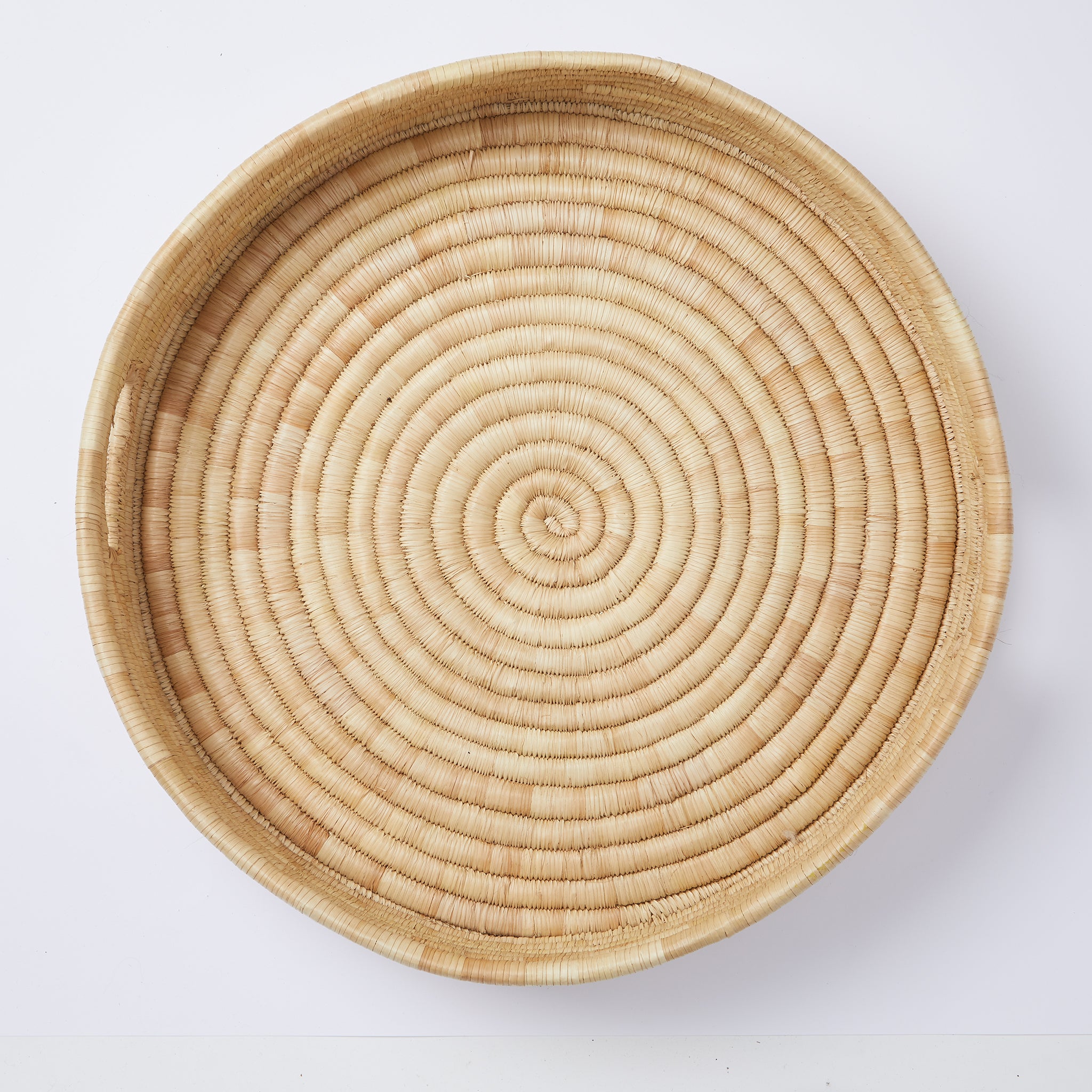 Tablett "Umi" Aufsicht. Stilvoll servieren: Das minimalistische und sehr stabile Tablett "Umi" wird sorgfältig aus Palmenblättern geflochten. Ein lässiger Allrounder für dein Zuhause.   Durchmesser: 50 cm Höhe: 10 cm